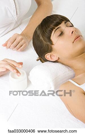 Stock Photograph - Woman receiving facial treatment, eyes closed. Fotosearch