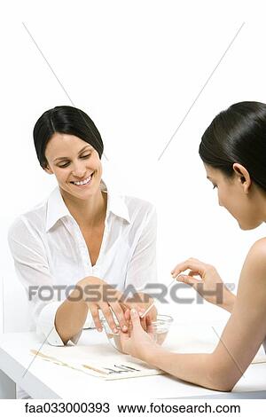 Stock Image - Woman receiving manicure, smiling. Fotosearch