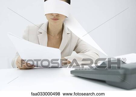 Stock Photo - Woman sitting at desk, tape from an adding machine wrapped around her head, holding document. Fotosearch