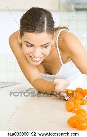 Stock Image - Woman spilling bowl of cherry tomatoes, smiling. Fotosearch