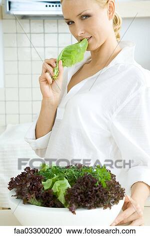 Woman standing in front of large salad bowl, eating lettuce, looking at camera View Large Photo Image Stock Image - Woman standing in front of large salad bowl, eating lettuce, looking at camera. Fotosearch
