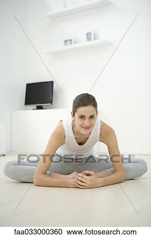 Stock Image - Woman stretching on the ground, smiling at camera. Fotosearch