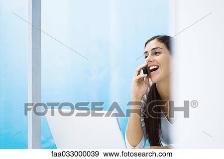Woman talking on cell phone, smiling, laptop, cropped View Large Photo Image Stock Photo - Woman talking on cell phone, smiling, laptop, cropped. Fotosearch