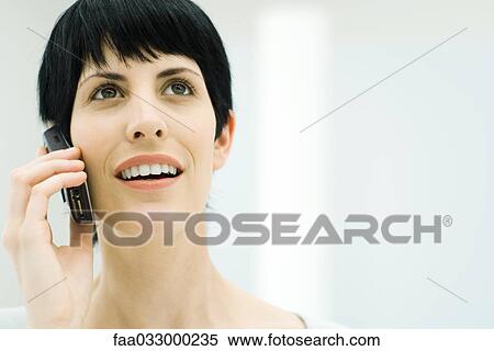 Stock Photography - Woman using cell phone, looking up, close-up. Fotosearch
