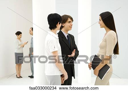 Young businessman introducing two business women to each other, smiling at each other View Large Photo Image Picture - Young businessman introducing two business women to each other, smiling at each other. Fotosearch