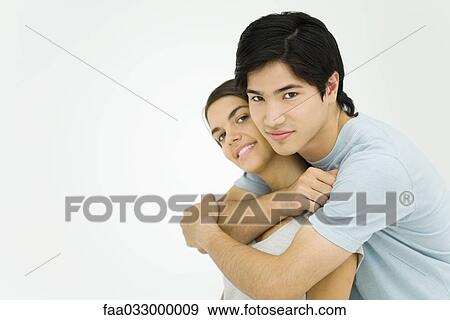Stock Photo - Young couple embracing, smiling at camera. Fotosearch