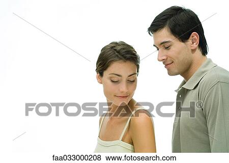 Stock Photo - Young couple with eyes closed, man standing behind woman, portrait. Fotosearch