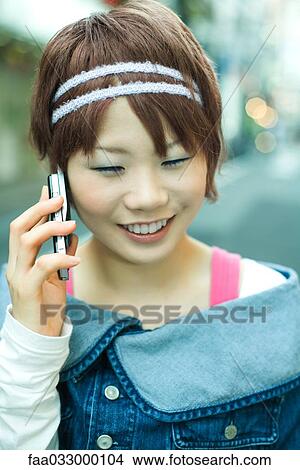 Young Japanese woman using cell phone, smiling View Large Photo Image Picture - Young Japanese woman using cell phone, smiling. Fotosearch