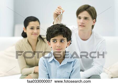 Young man and woman with boy, trying out head massager View Large Photo Image Stock Photo - Young man and woman with boy, trying out head massager. Fotosearch