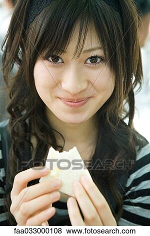 Young woman eating sandwich, smiling at camera View Large Photo Image Stock Photo - Young woman eating sandwich, smiling at camera. Fotosearch