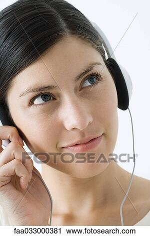 Young woman listening to headphones, smiling, looking away View Large Photo Image Stock Image - Young woman listening to headphones, smiling, looking away. Fotosearch
