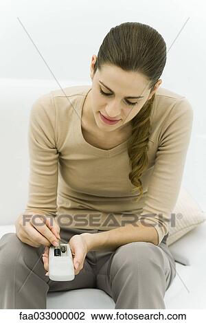 Young woman putting batteries in a remote control, looking down View Large Photo Image Stock Image - Young woman putting batteries in a remote control, looking down. Fotosearch