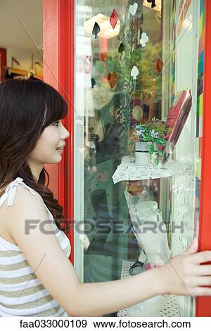 Stock Photo - Young woman window shopping, side view. Fotosearch