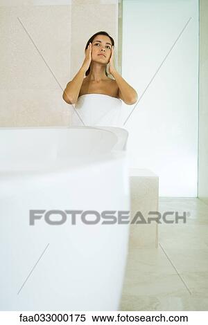 Young woman wrapped in towel, looking up and away, touching face View Large Photo Image Stock Photography - Young woman wrapped in towel, looking up and away, touching face. Fotosearch