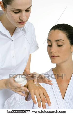 Stock Photo - Beautician applying moisturizer to woman's hand. Fotosearch
