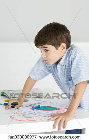 Boy leaning on table, holding crayon, colorful drawing on paper and the table View Large Photo Image Stock Photo - Boy leaning on table, holding crayon, colorful drawing on paper and the table. Fotosearch