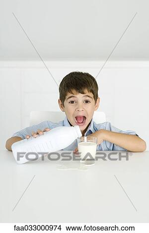 Boy pouring milk into glass, mouth open, spilled milk on table View Large Photo Image Picture - Boy pouring milk into glass, mouth open, spilled milk on table. Fotosearch