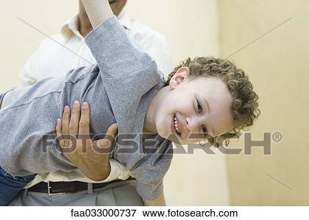 Stock Photo - Boy pretending to be a plane, being held by his father. Fotosearch