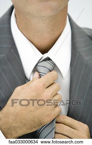 Businessman adjusting neck tie, close-up, cropped View Large Photo Image Picture - Businessman adjusting neck tie, close-up, cropped. Fotosearch