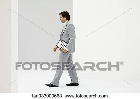 Stock Image - Businessman carrying document, side view. Fotosearch