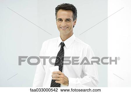 Businessman holding cup, smiling, portrait View Large Photo Image Stock Image - Businessman holding cup, smiling, portrait. Fotosearch