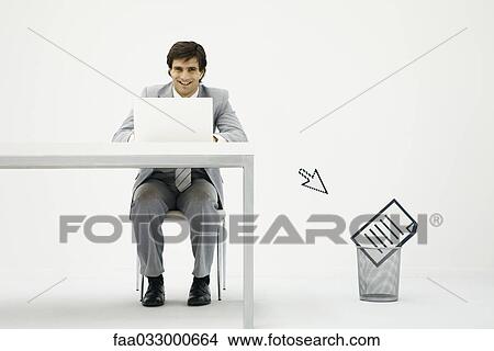 Businessman working on laptop, cursor pointing toward document in wastepaper basket View Large Photo Image Picture - Businessman working on laptop, cursor pointing toward document in wastepaper basket. Fotosearch