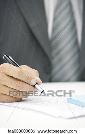 Stock Photography - Businessman writing on document, cropped view of hand. Fotosearch