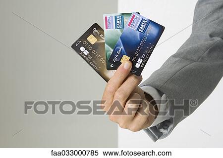 Stock Photography - Businessman's hand holding several credit cards, cropped view. Fotosearch