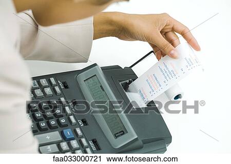 Stock Image - Businesswoman using adding machine, holding printout, cropped view. Fotosearch