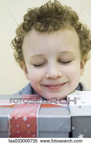 Child resting head on gift wrapped boxes, eyes closed and smiling View Large Photo Image Stock Photography - Child resting head on gift wrapped boxes, eyes closed and smiling. Fotosearch