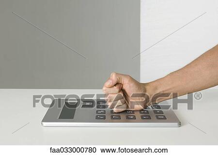 Clenched fist hitting oversized calculator, cropped view View Large Photo Image Stock Image - Clenched fist hitting oversized calculator, cropped view. Fotosearch