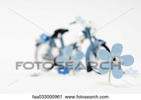 Stock Image - Craft flowers, toy bike in background. Fotosearch