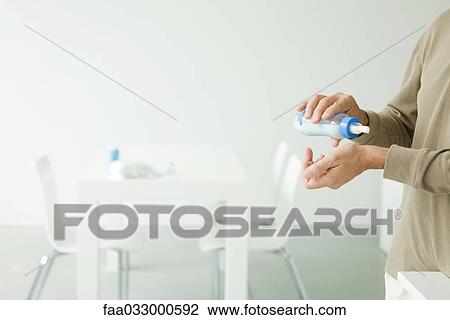 Stock Image - Father holding baby bottle, checking temperature on wrist, cropped view. Fotosearch