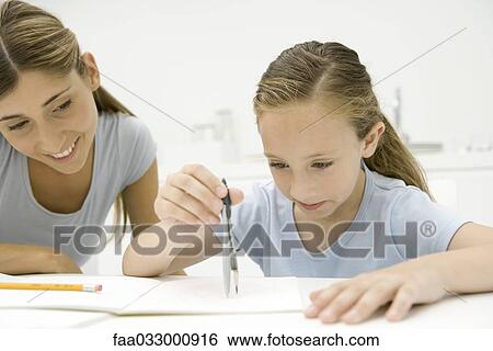 Stock Photograph - Girl using compass to do geometry, mother watching and smiling. Fotosearch