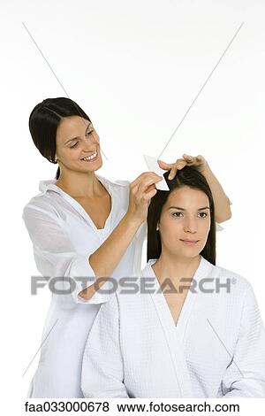 Stock Photo - Hair stylist combing woman's hair, both looking away. Fotosearch