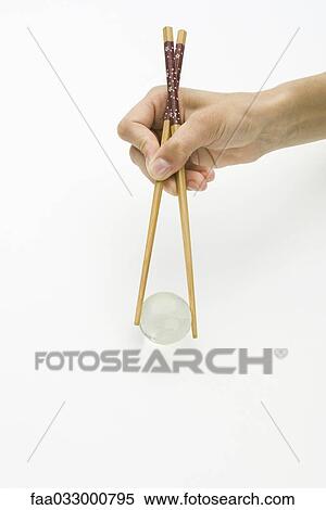 Stock Photography - Hands using chopsticks to hold transparent globe, cropped view. Fotosearch