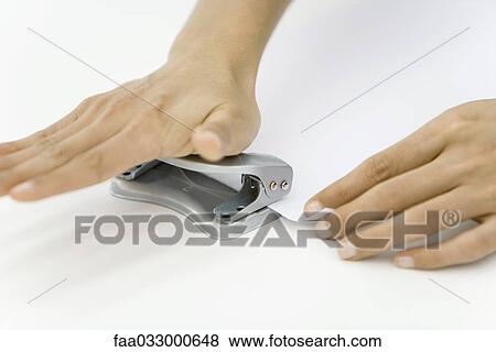 Stock Photo - Hands using hole puncher. Fotosearch