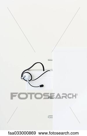 Headset hanging from open drawer of a filing cabinet, side view View Large Photo Image Stock Photo - Headset hanging from open drawer of a filing cabinet, side view. Fotosearch
