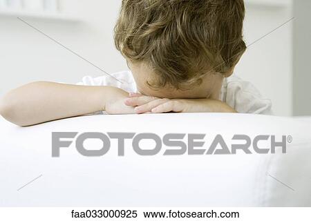 Stock Photography - Little boy sitting with his head down on his arms. Fotosearch