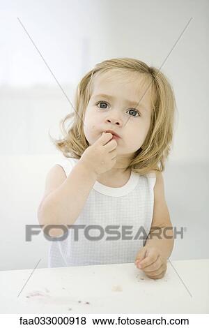 Little girl sitting at messy table, wiping a crumb off her lip View Large Photo Image Stock Photo - Little girl sitting at messy table, wiping a crumb off her lip. Fotosearch