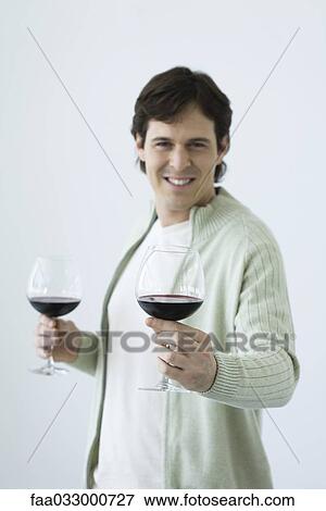 Stock Photo - Man holding two glasses of wine, holding out one toward camera. Fotosearch