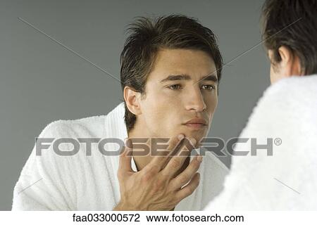 Man in bathrobe looking in mirror, inspecting skin View Large Photo Image Stock Image - Man in bathrobe looking in mirror, inspecting skin. Fotosearch