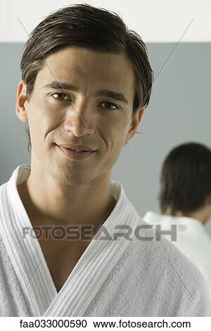 Stock Image - Man in bathrobe smiling at camera, portrait. Fotosearch