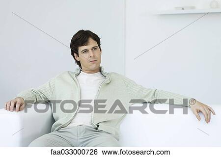 Man relaxing on couch, looking away View Large Photo Image Stock Photograph - Man relaxing on couch, looking away. Fotosearch