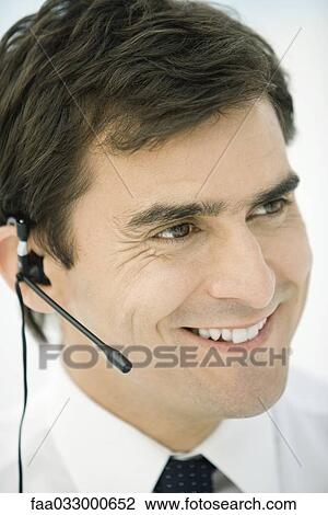 Man wearing headset, smiling, looking away View Large Photo Image Stock Image - Man wearing headset, smiling, looking away. Fotosearch