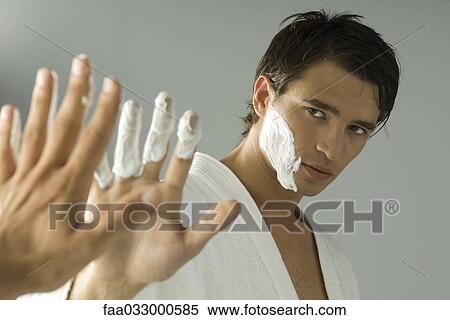 Stock Photography - Man with shaving cream on his face and fingers, looking at self in mirror. Fotosearch