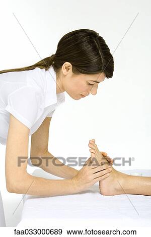 Stock Photo - Massage therapist performing foot massage, cropped view. Fotosearch