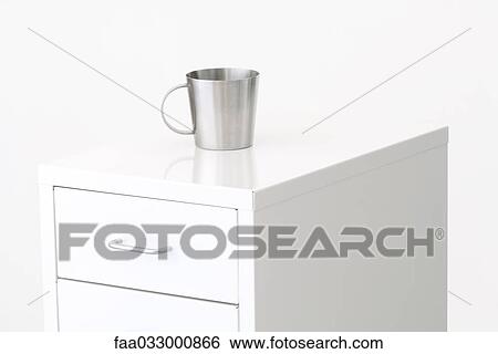 Stock Photograph - Metal cup on top of a filing cabinet. Fotosearch
