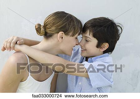 Picture - Mother and son touching noses, boy's arms around woman, side view. Fotosearch