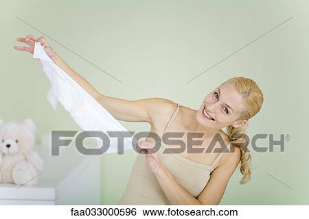 Stock Photograph - New mother holding up diaper, smiling at camera, head tilted. Fotosearch